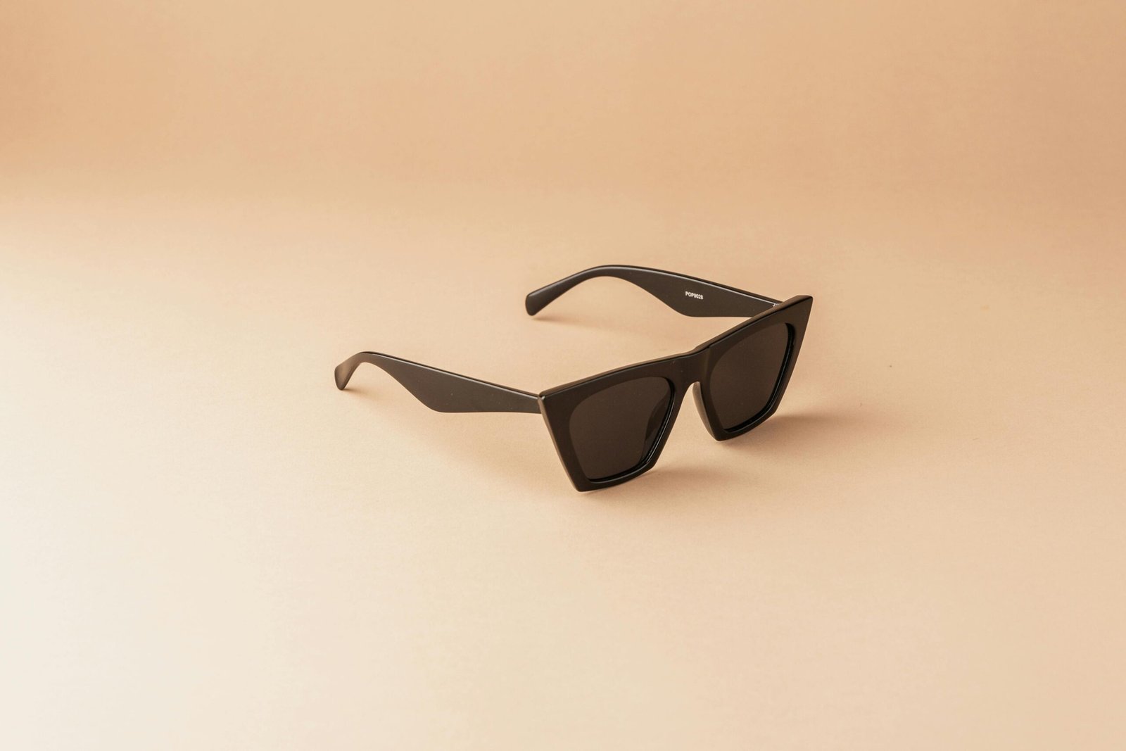 Modern black sunglasses with a sleek design on a neutral background, perfect for lifestyle themes.
